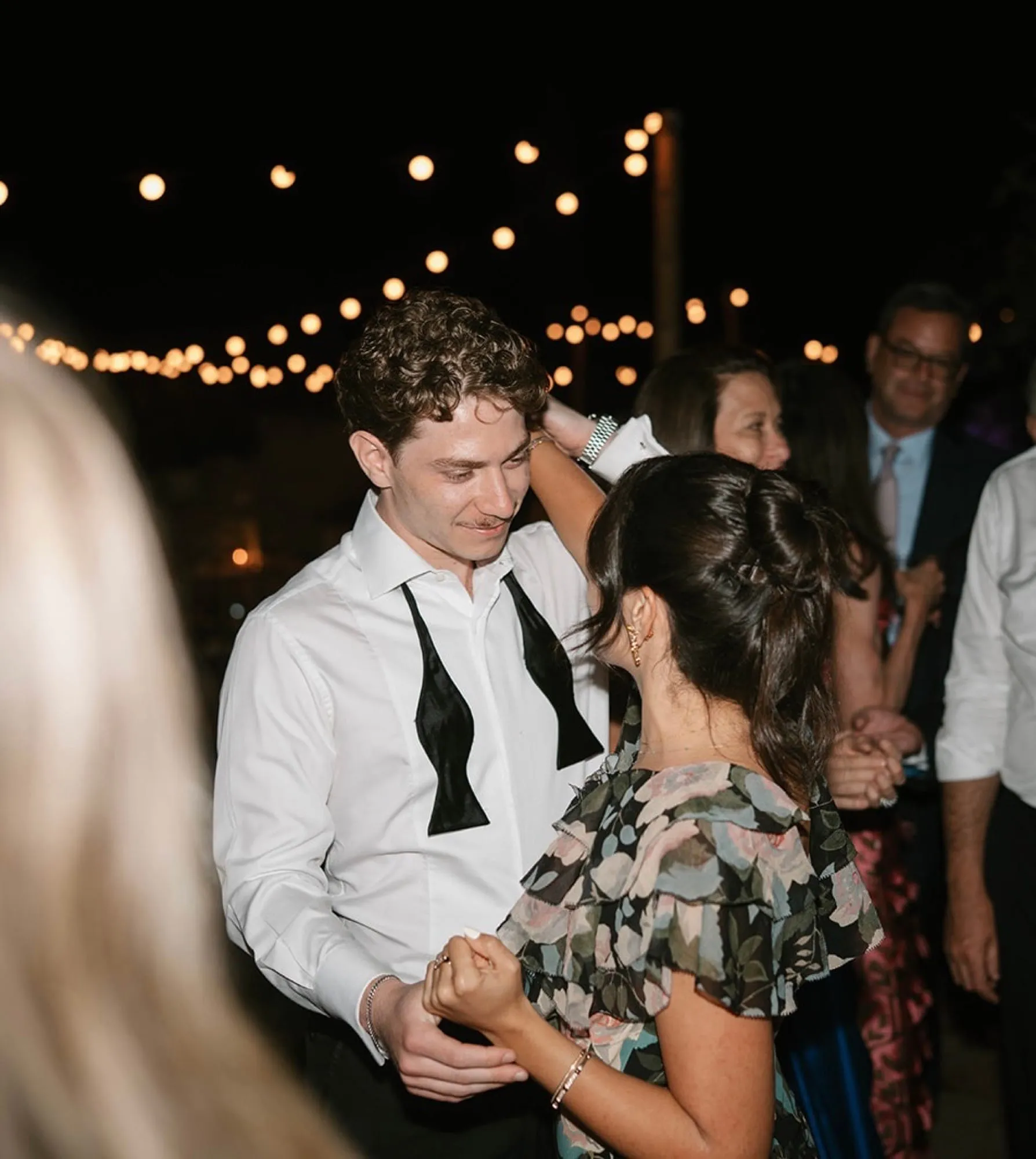 Lauren and Ben dancing under string lights at an evening reception
