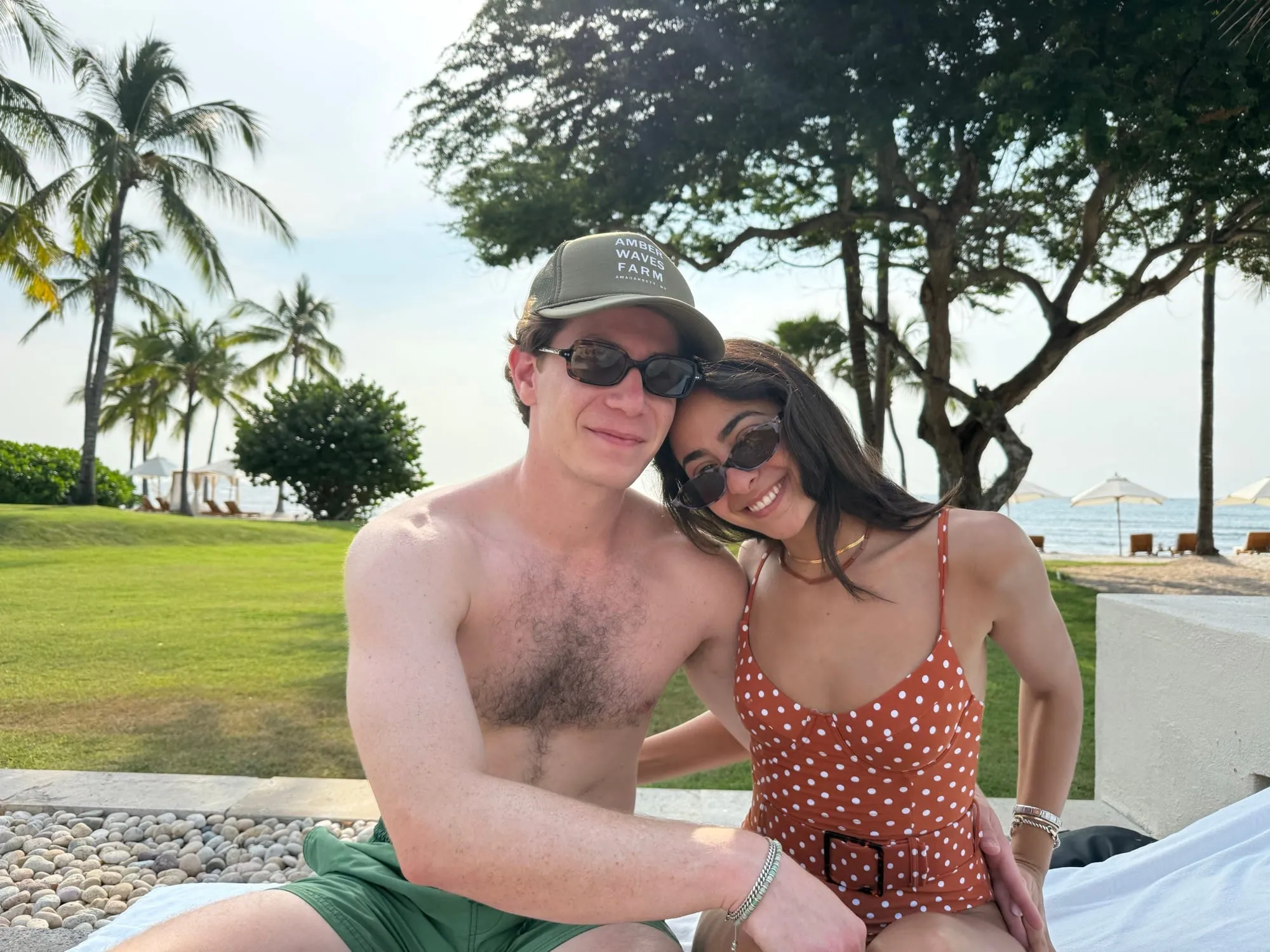 Lauren and Ben on a lawn under palm trees on a tropical trip