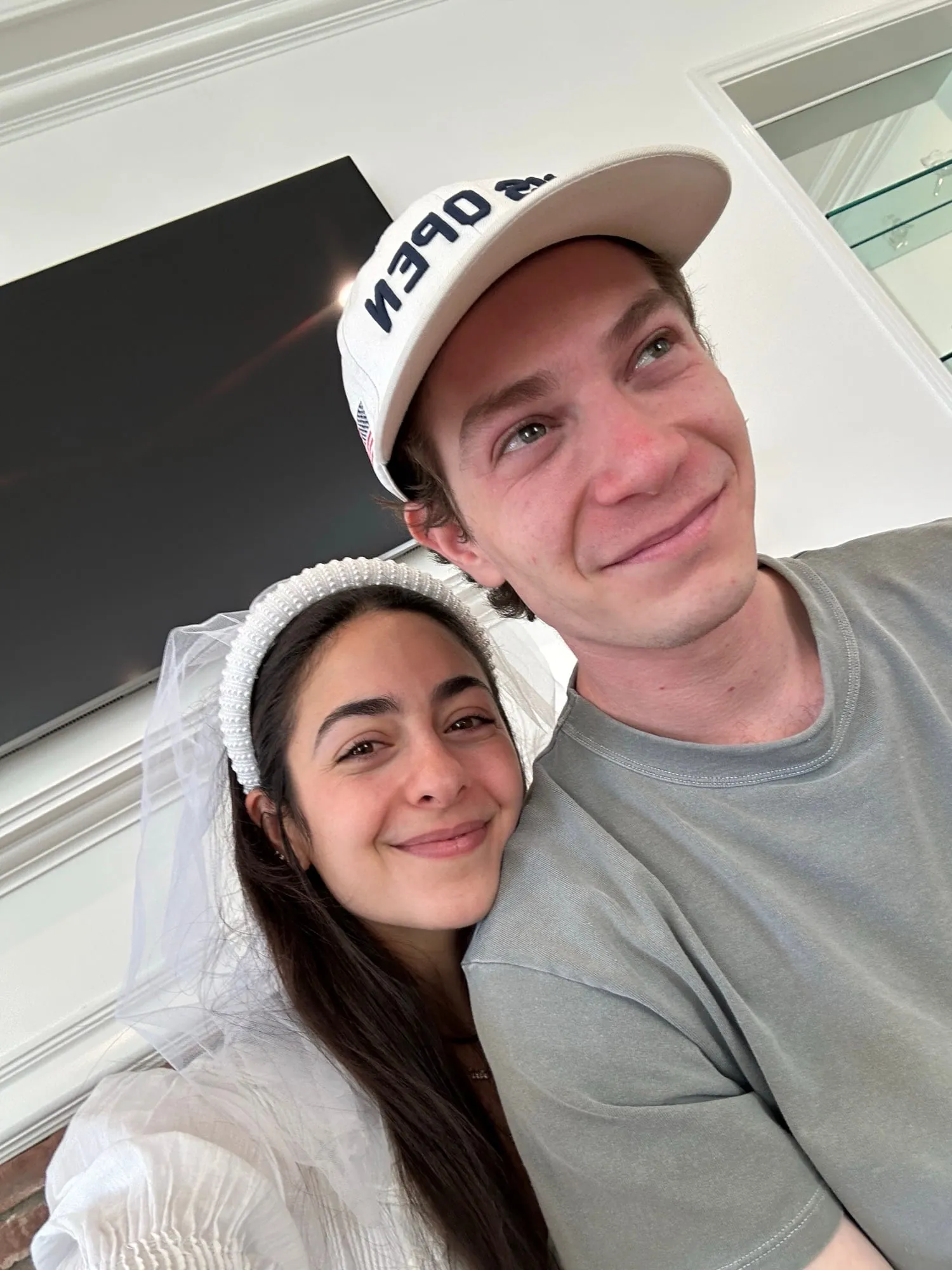 A selfie of Lauren in a bridal veil headband beside Ben in a baseball cap