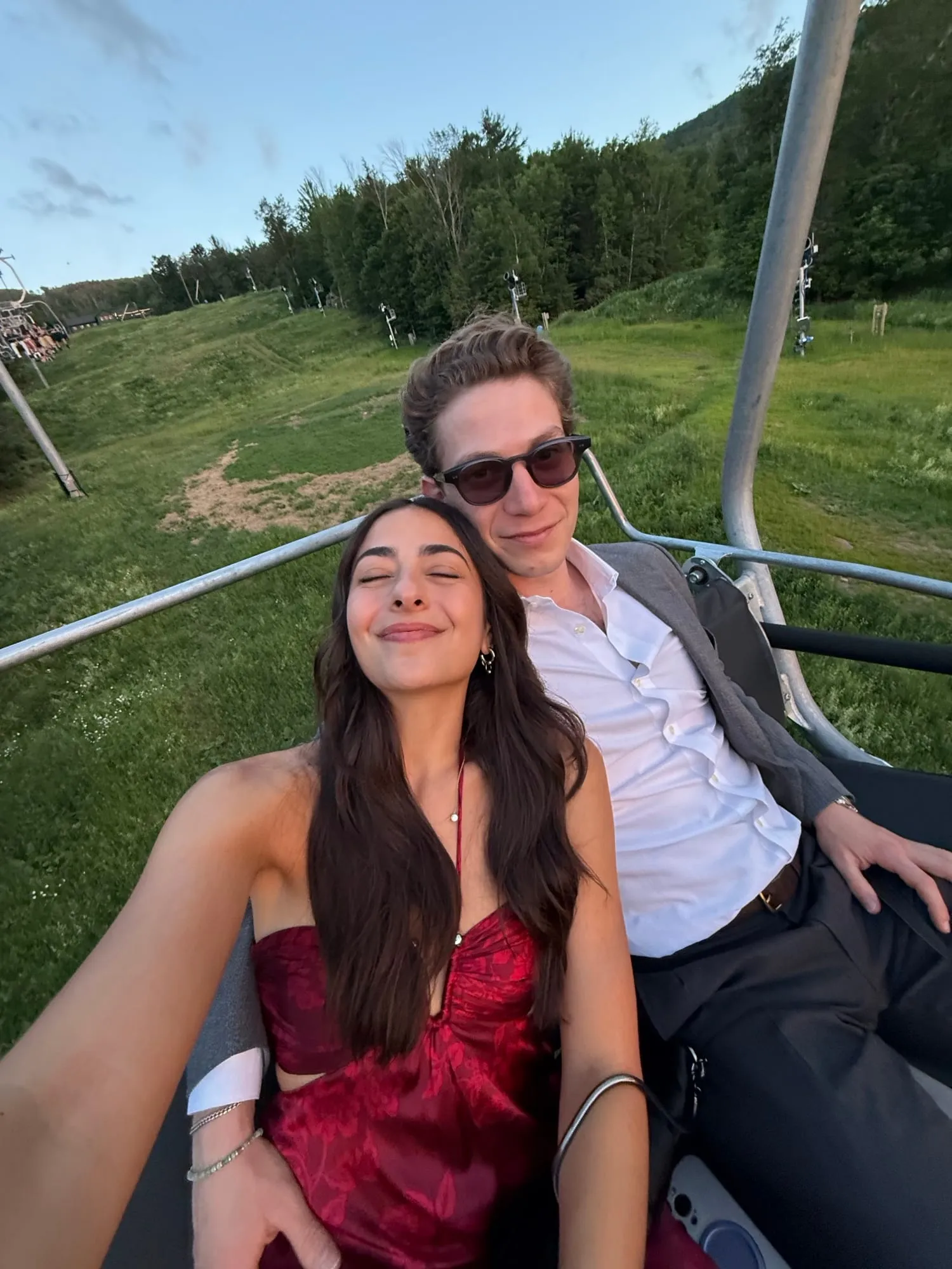 Lauren and Ben riding a chairlift over green hills