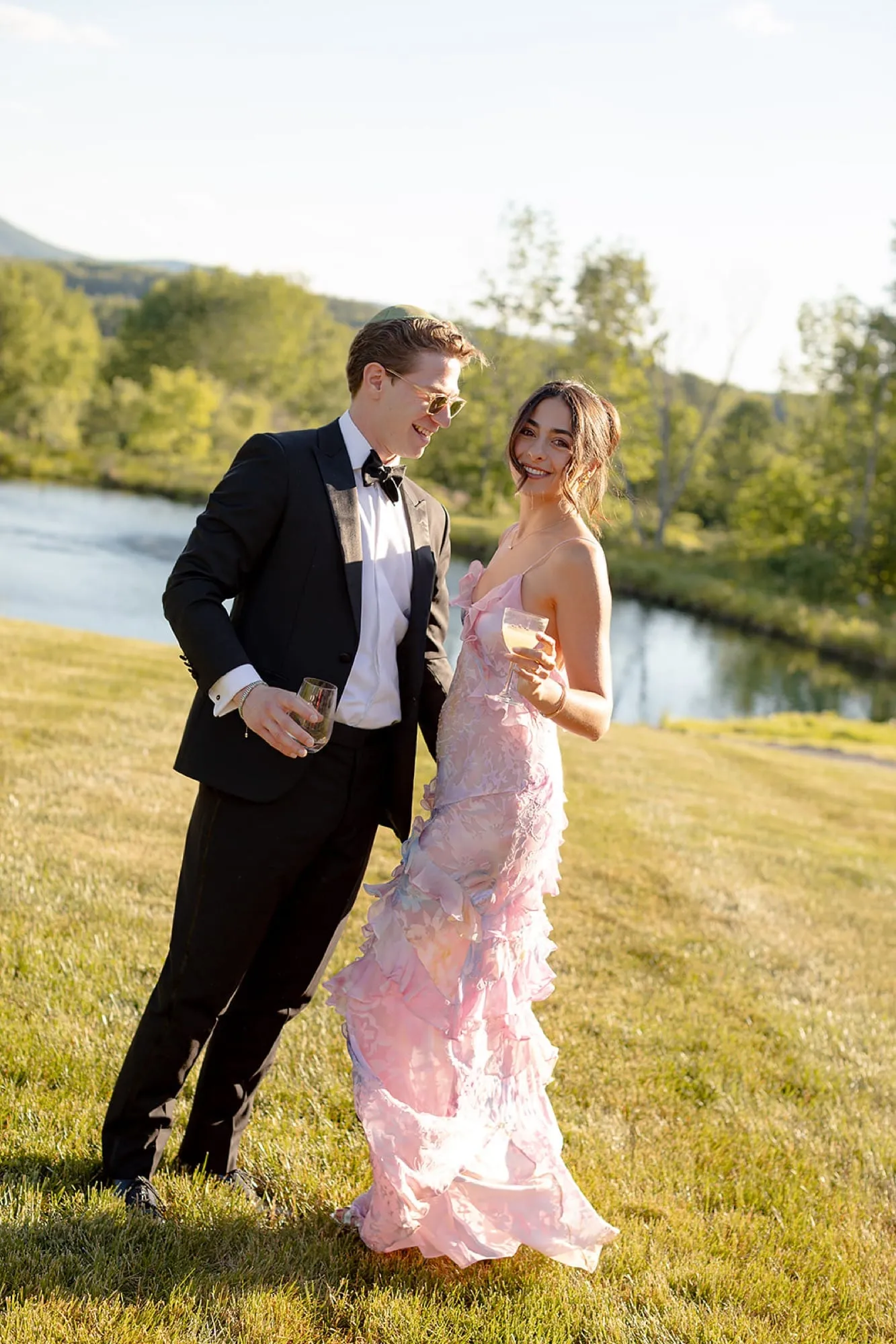 Lauren in a pink gown and Ben in black tie at a riverside wedding